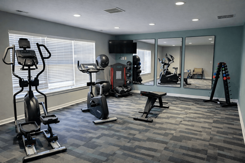 A spacious gym with a variety of equipment including treadmills, exercise bikes, and weight machines.