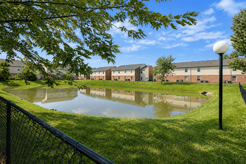 A pond in front of a building with a lamp post on the right.