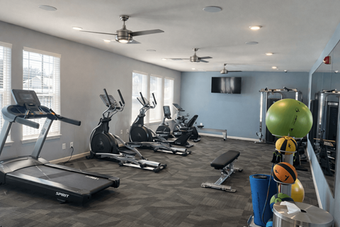 A gym with a variety of equipment including treadmills, exercise bikes, and weightlifting equipment.