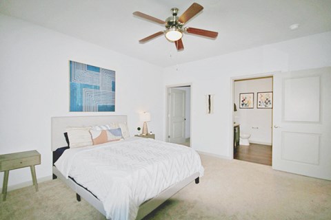 a bedroom with a large white bed and a ceiling fan