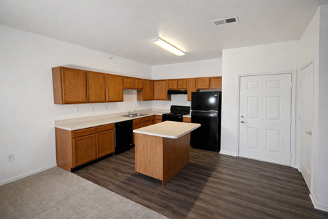 A kitchen with wooden cabinets and a black fridge.