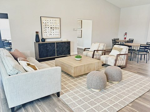 A living room with a grey sofa, a wooden coffee table, and a dining table with chairs.