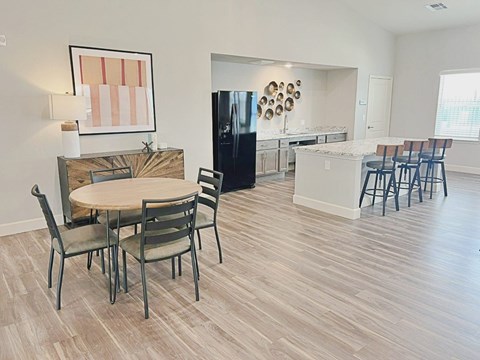 A kitchen with a table and chairs in the foreground and a refrigerator in the background.