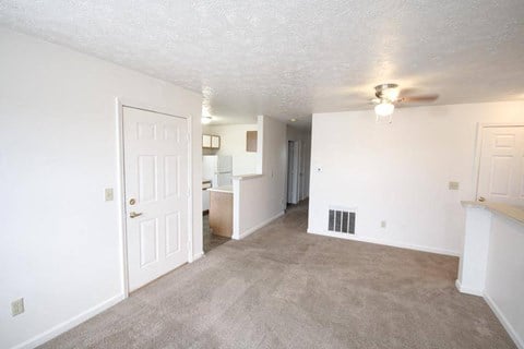 A spacious room with a carpeted floor and a ceiling fan.