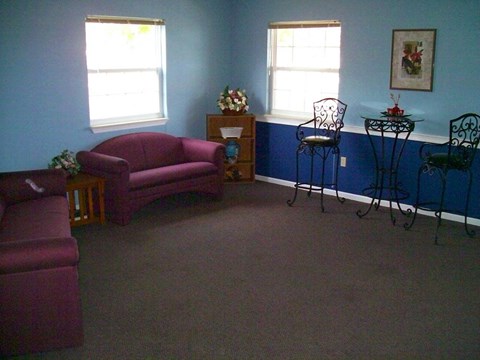 A living room with a purple couch and a table with chairs.