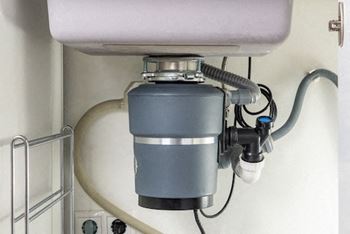 A grey water filter is installed under a sink.