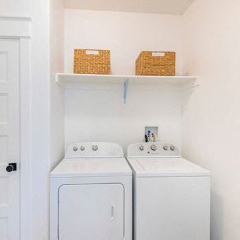 Two white washing machines in a small laundry room.