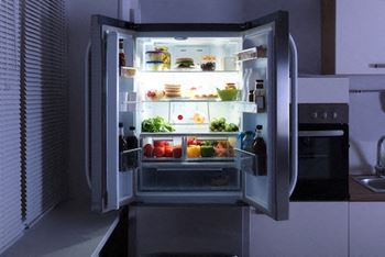 A refrigerator is open and filled with food.