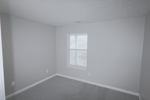 A room with a window and carpeted floor.