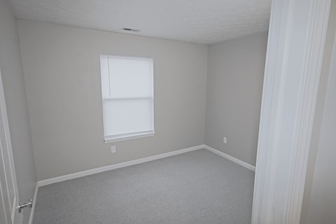 A room with a window and carpeted floor.