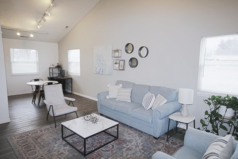 A living room with a blue couch, a white coffee table, and a white chair.