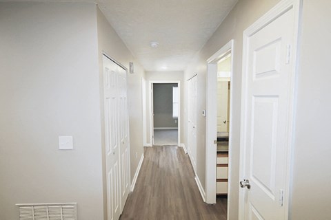 A long hallway with white doors and a light switch on the wall.