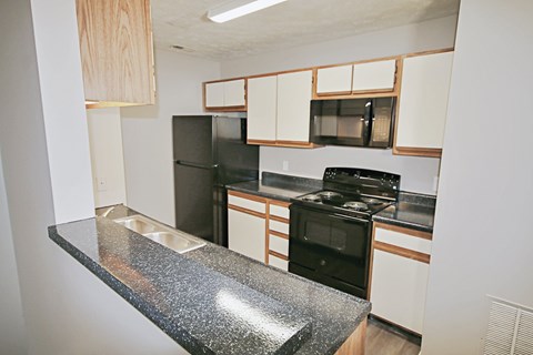 A kitchen with black appliances and white cabinets.