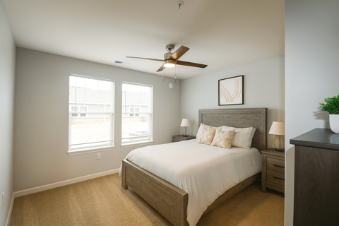 A bedroom with a bed, nightstand, and a ceiling fan.