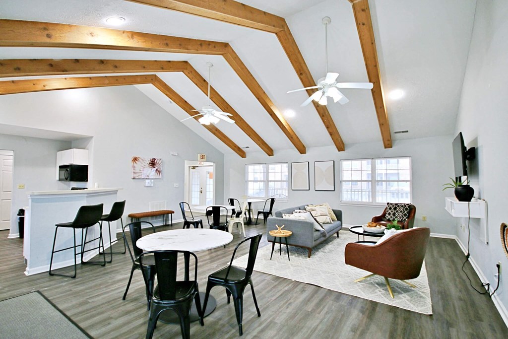 clubhouse lounge area with tables, a couch, and tv at canterbury house apartments in warsaw