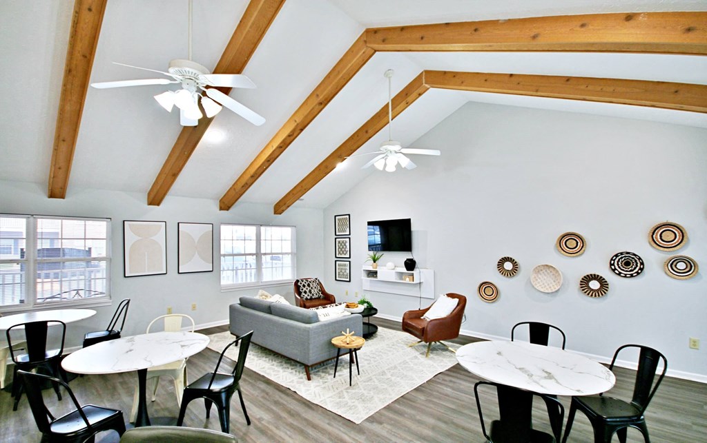clubhouse lounge area with tables, a couch, and tv at canterbury house apartments in warsaw