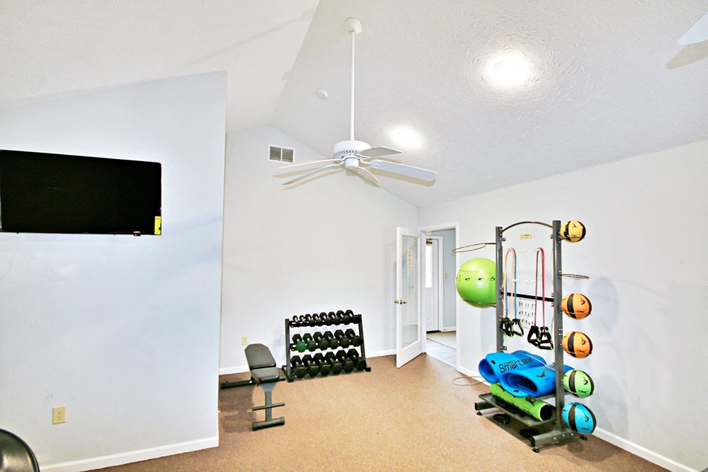 a workout room with a ceiling fan and weights and a tv at Canterbury house apartments in warsaw