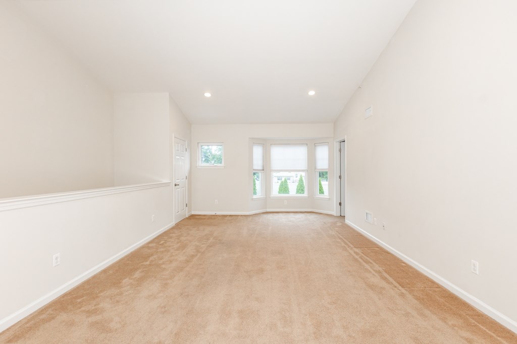 a spacious living room with white walls and a beige carpet