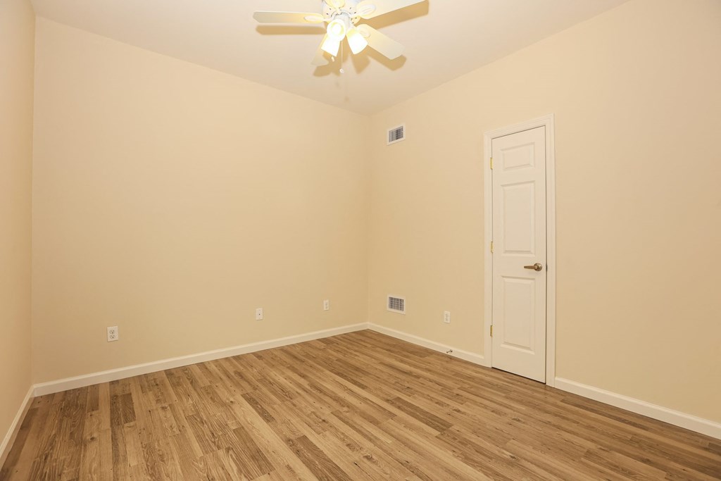 a bedroom with a ceiling fan and wood flooring