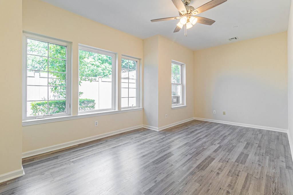 an empty living room with wood floors and a ceiling fan