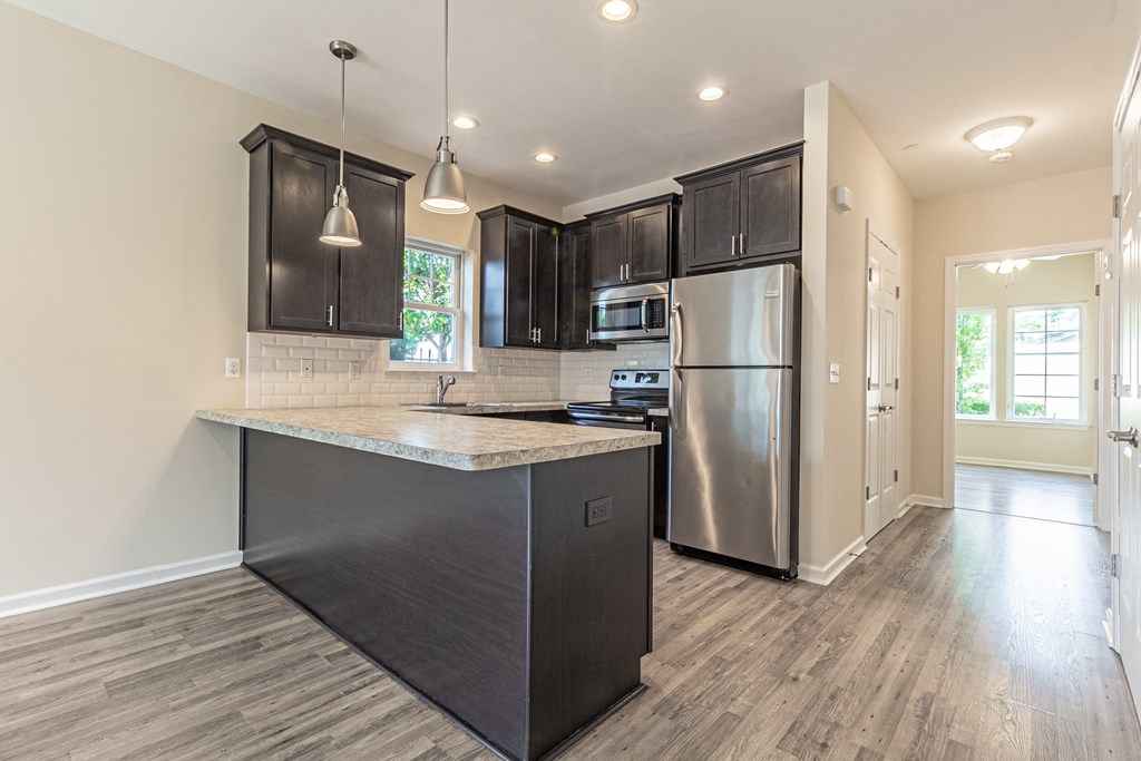 an empty kitchen with stainless steel appliances and black cabinets