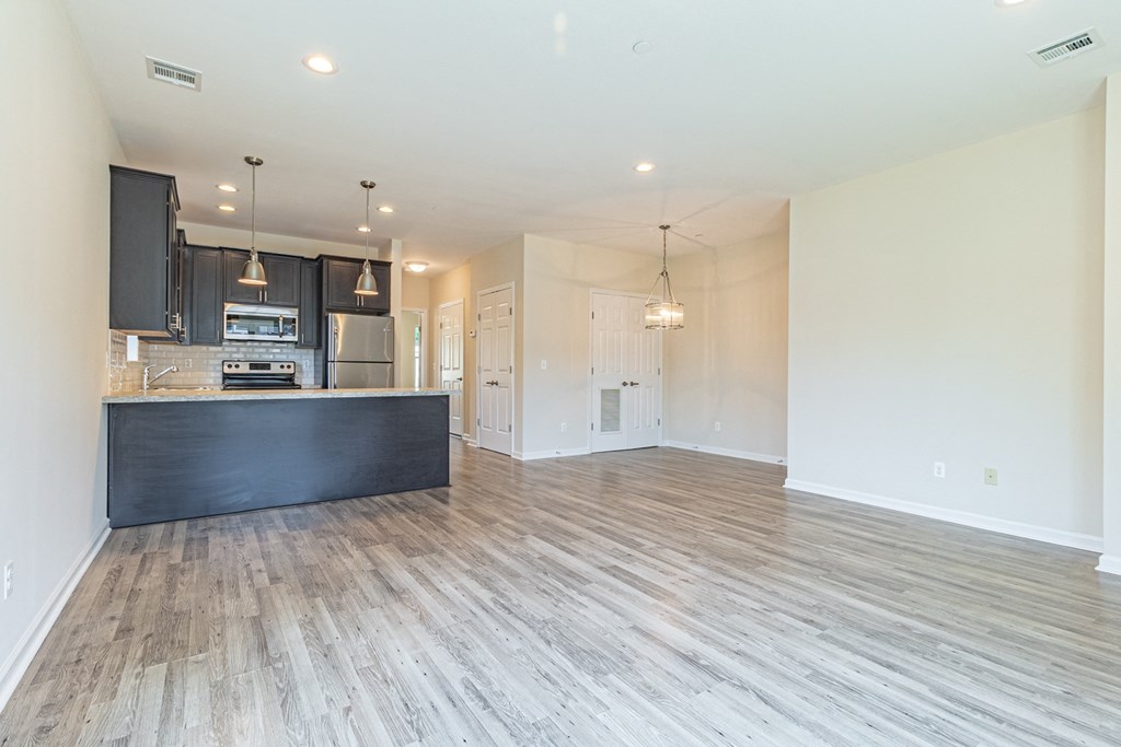 an open kitchen and living room with wood flooring
