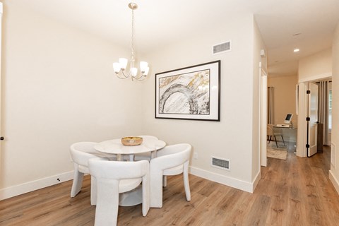 A dining room with a white table and chairs.