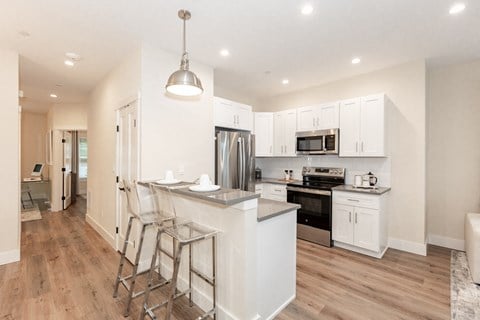 A modern kitchen with white cabinets and a wooden floor.