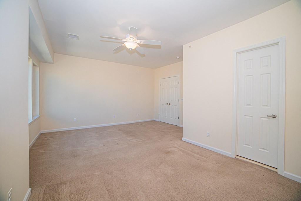 an empty living room with carpet and a ceiling fan