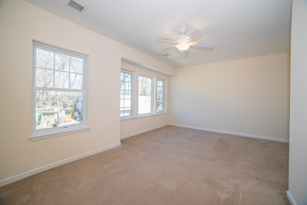 a bedroom with a ceiling fan and three windows
