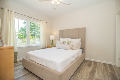 A bedroom with a large bed and a window with curtains.