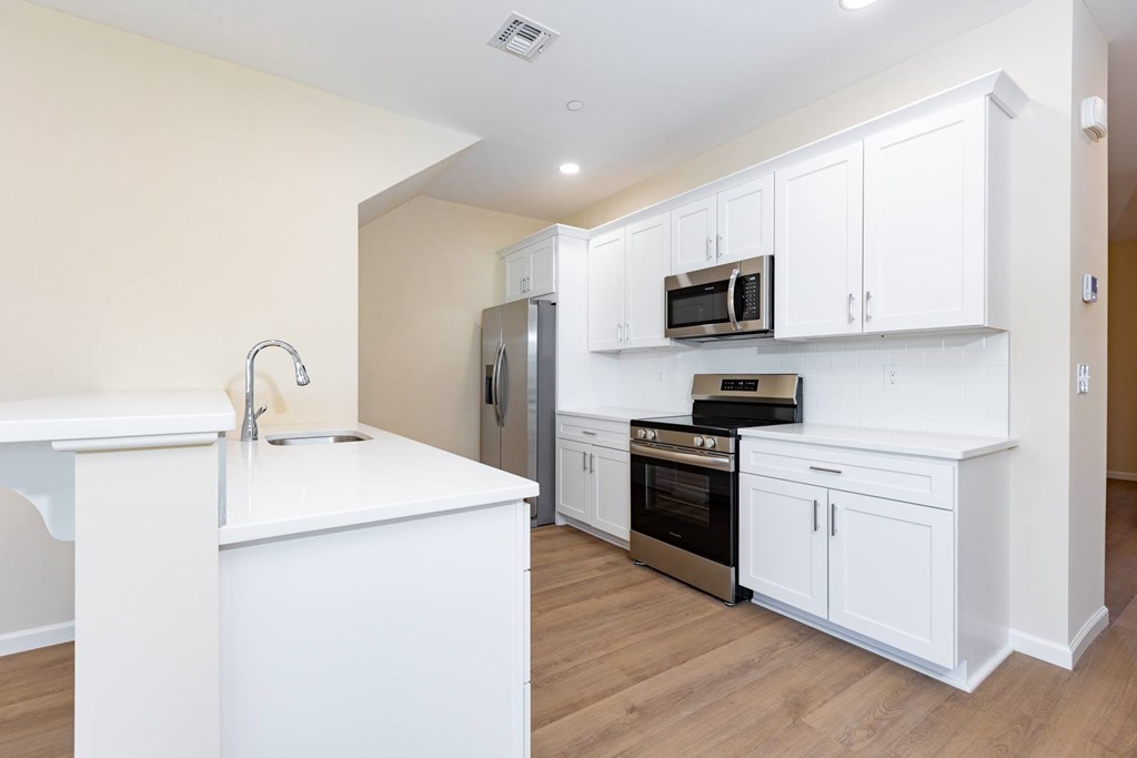 A kitchen with white cabinets and appliances.