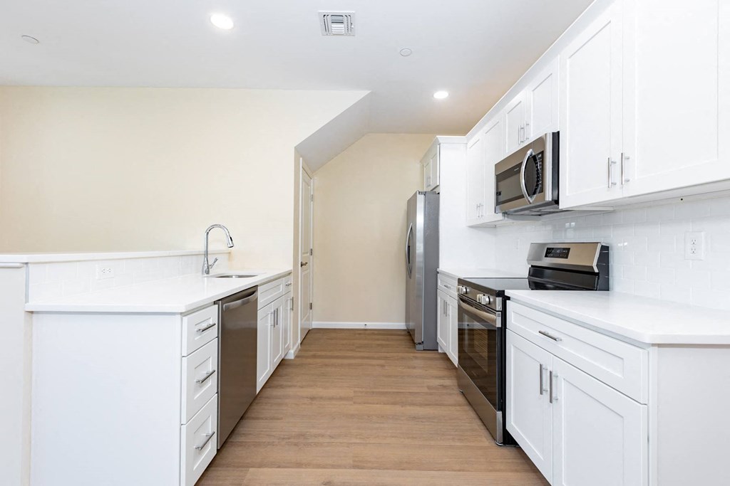 A kitchen with white cabinets and appliances.