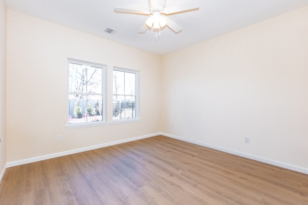 Empty room with a ceiling fan and two windows.
