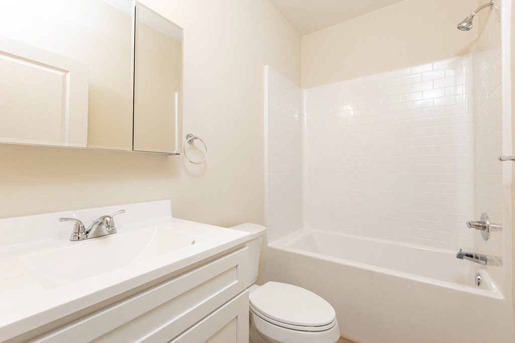 A white bathroom with a toilet, sink, and bathtub.