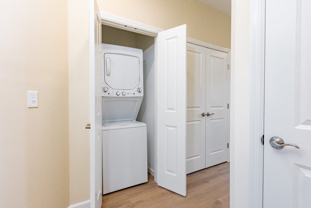 A white refrigerator is in a narrow hallway.