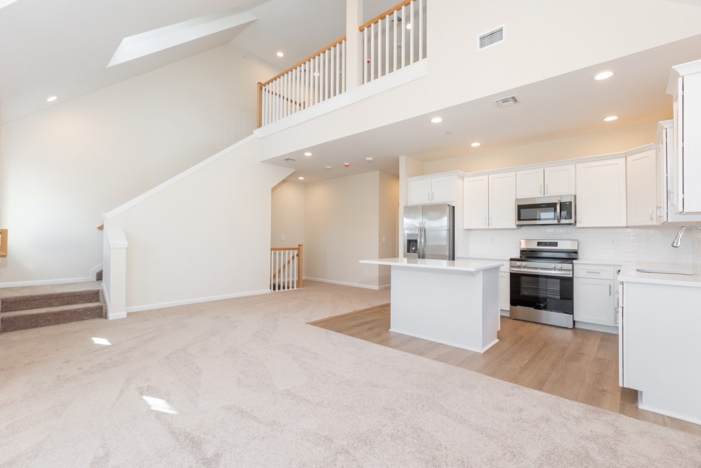 A spacious, well-lit open-plan living and kitchen area with a staircase.