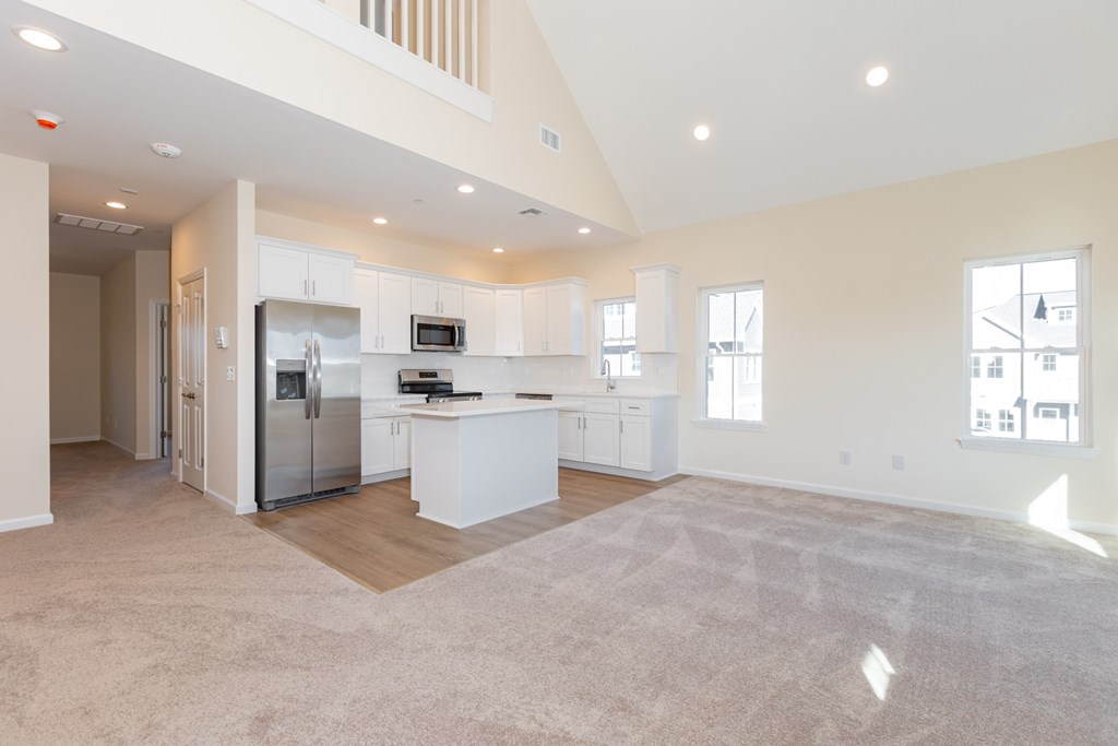 A spacious kitchen with white cabinets and a refrigerator.