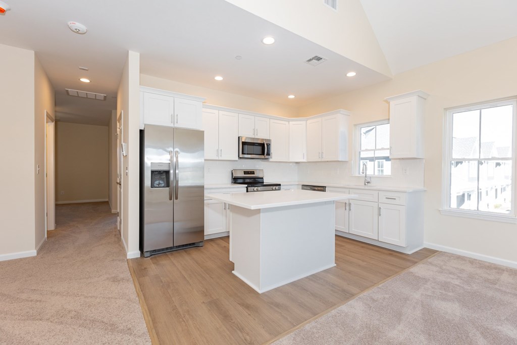 A kitchen with white cabinets and a refrigerator.