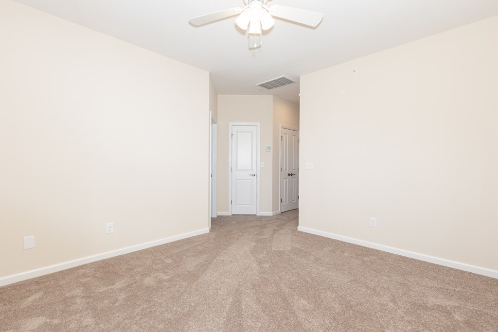 A room with a ceiling fan and carpeted floor.