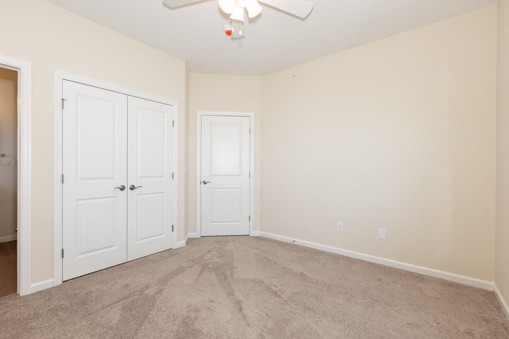 A room with a ceiling fan and two doors.