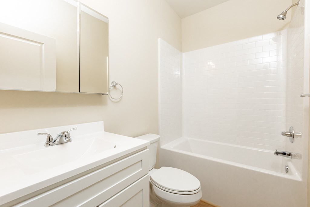 A white bathroom with a toilet, sink, and bathtub.