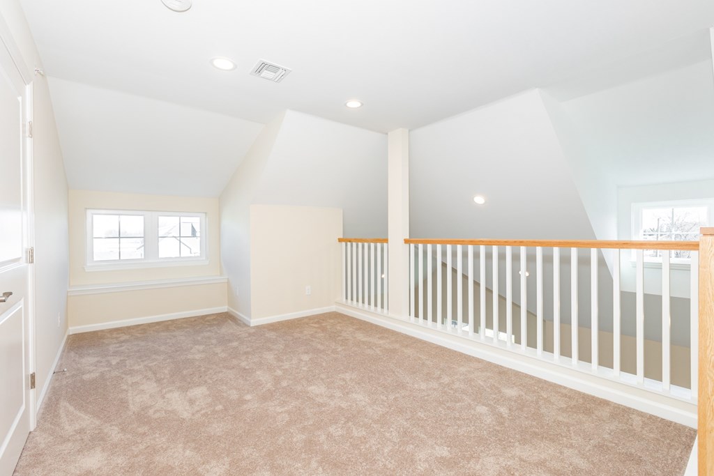 A spacious room with a carpeted floor and a white railing.