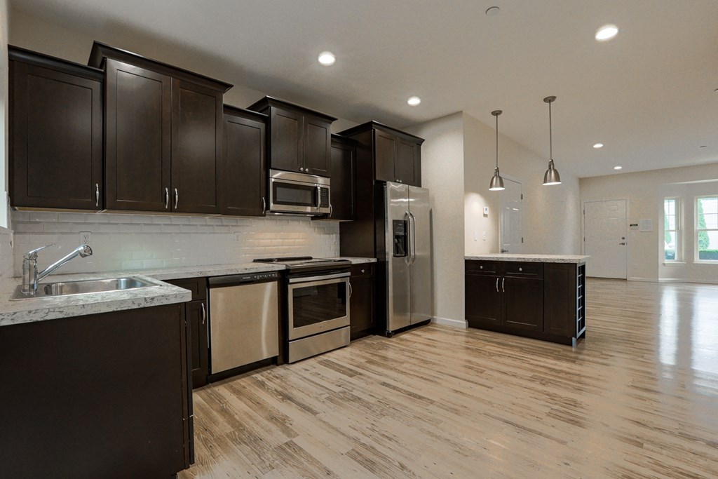 a large kitchen with black cabinets and stainless steel appliances