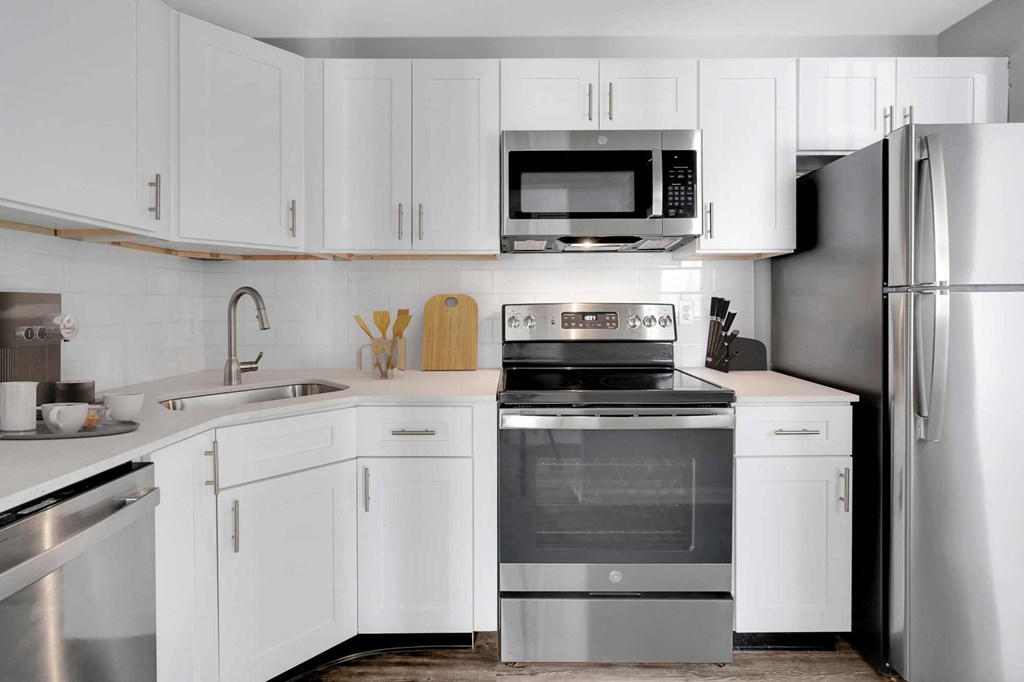 a white kitchen with stainless steel appliances and white cabinets