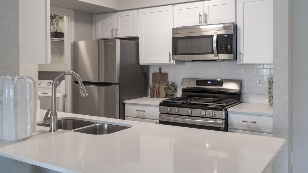 a white kitchen with stainless steel appliances and a sink