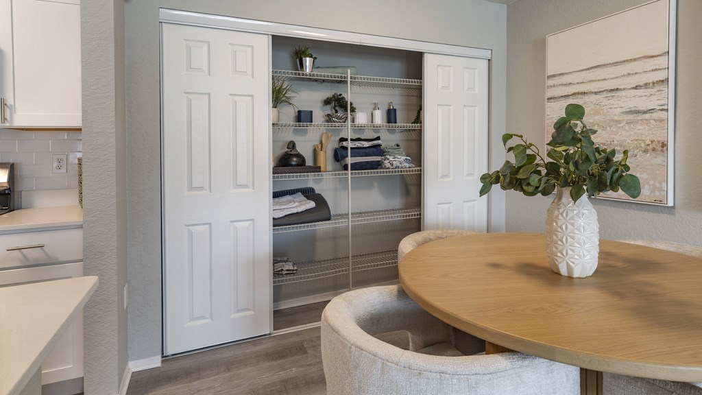 a dining room with a table and a closet with shelves