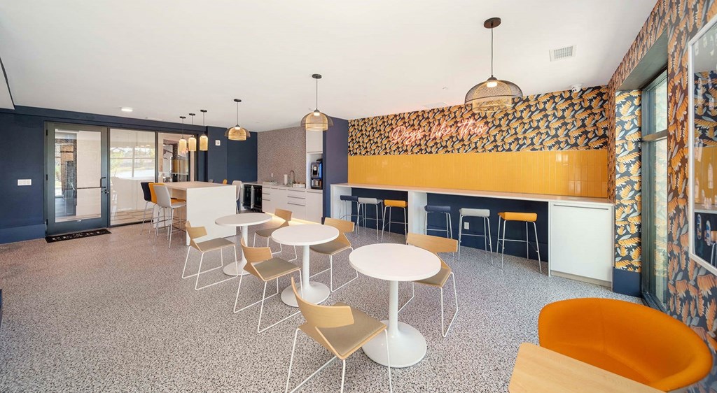 a seating area with tables and chairs in the clubhouse at The Pearl Apartments in Naples