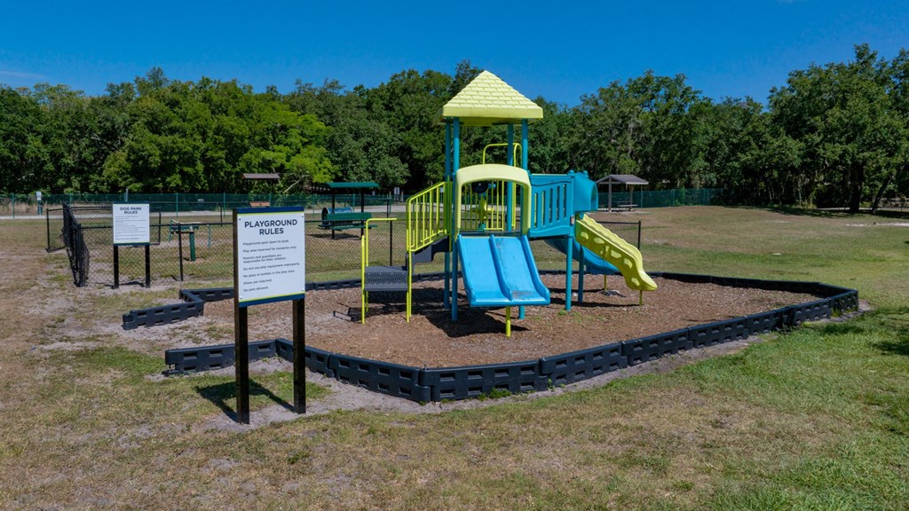 a playground with a yellow and blue playset and a sign