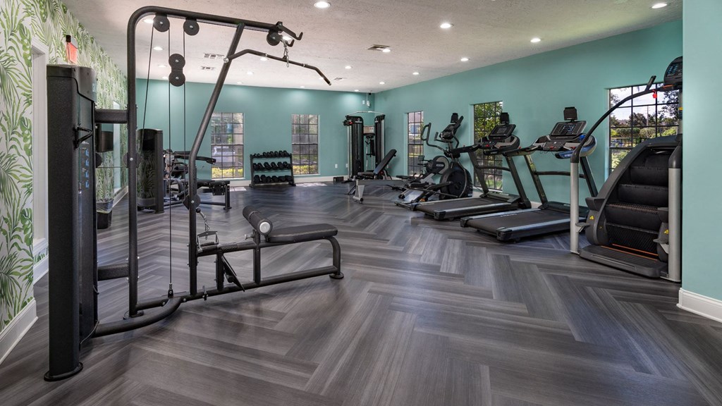 a gym with cardio machines and weights on a wooden floor